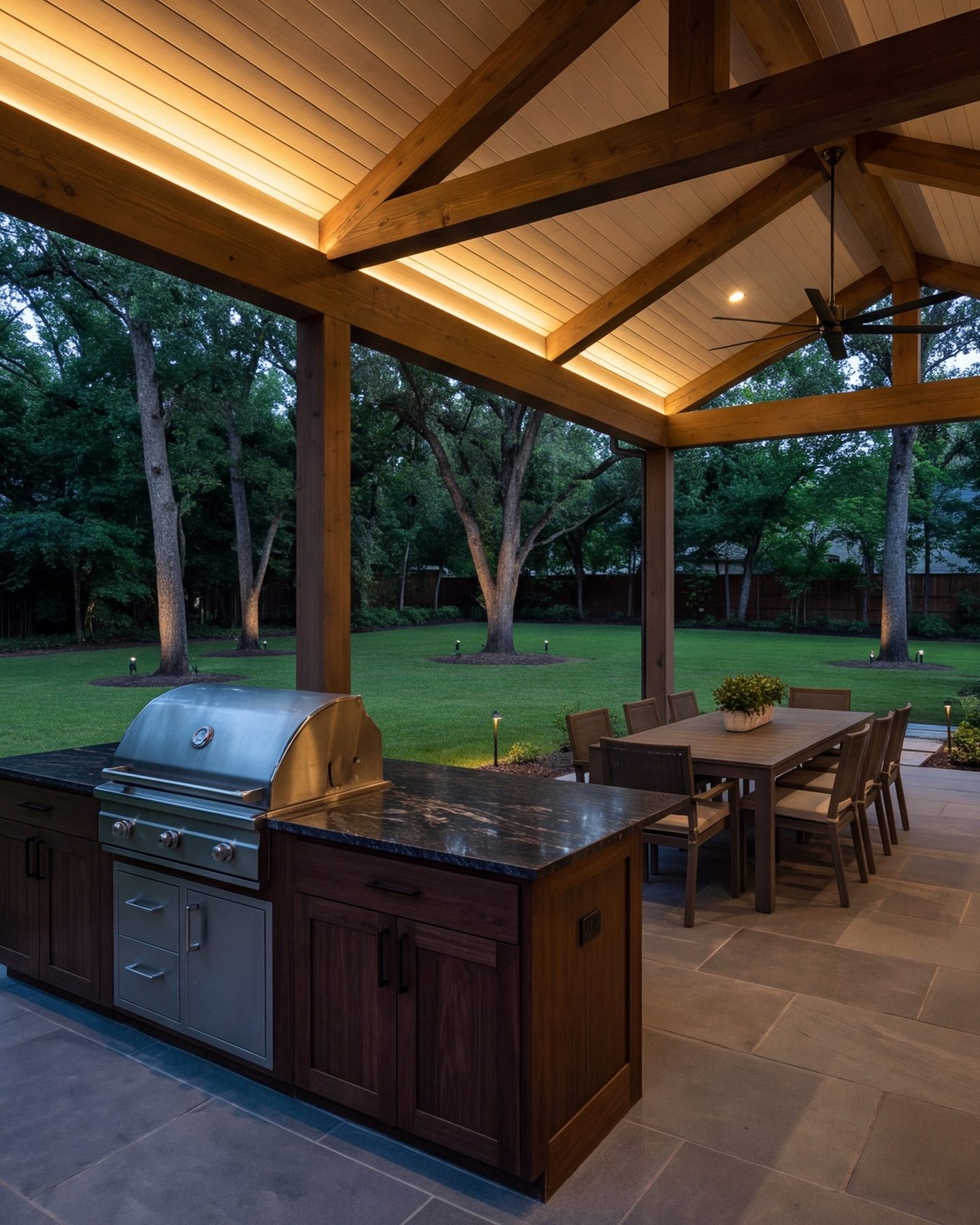 Covered outdoor kitchen and dining terrace at dusk